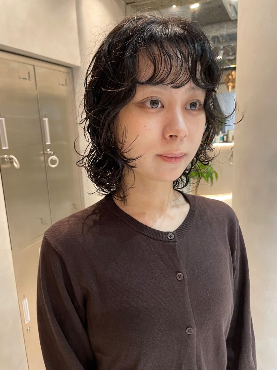 サロン室内で撮影した癖毛風パーマの正面ショット、茶色ニットと自然な毛束感