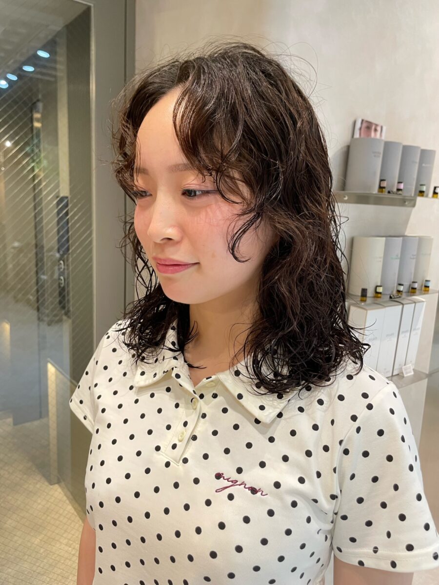黒髪ミディアムのゆるやかな無造作パーマ、川崎美容室の店内で撮影